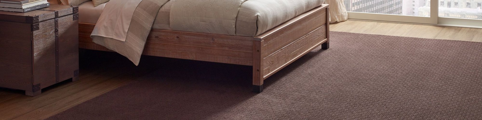 bedroom with trunk side table and brown area rug